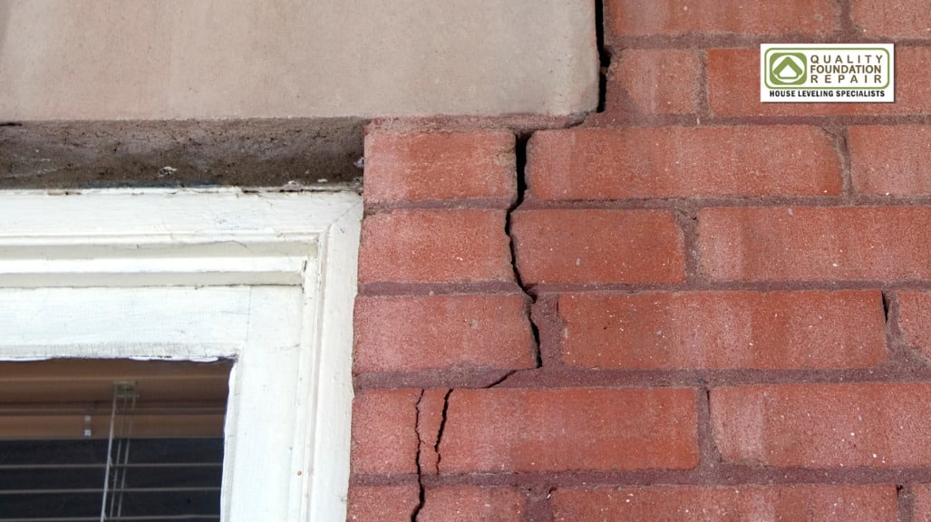 Quality Foundation Repair Austin inspecting a vertical crack running through brick beside a window.