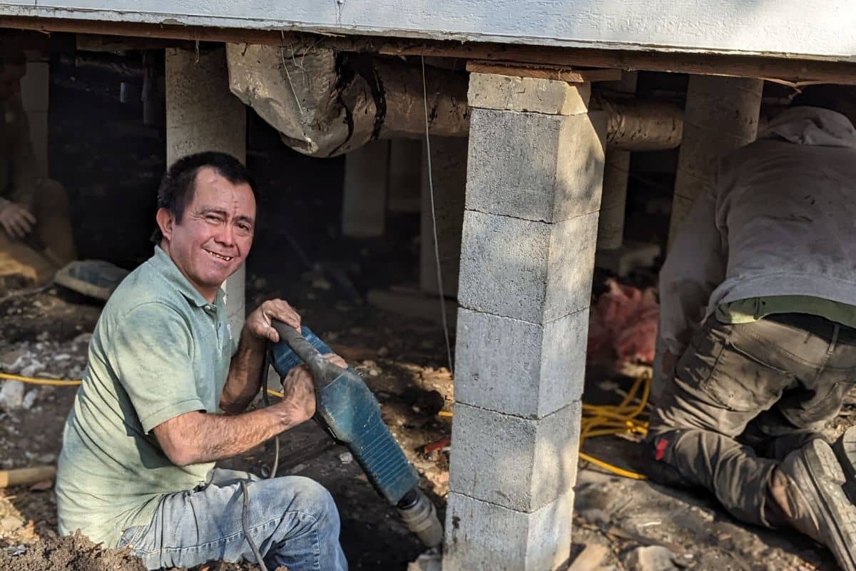 Quality Foundation Repair Austin crew breaking out concrete beneath a house during a repair.