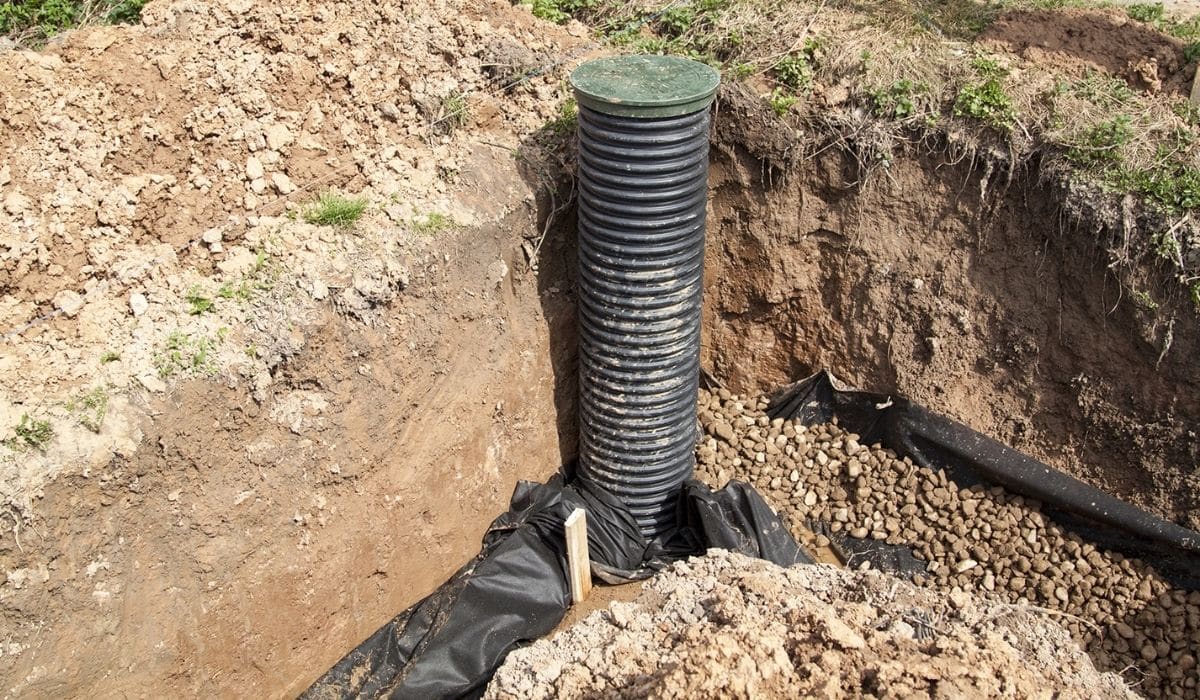Quality Foundation Repair Austin installing a crawl space drainage system with a corrugated pipe and gravel.
