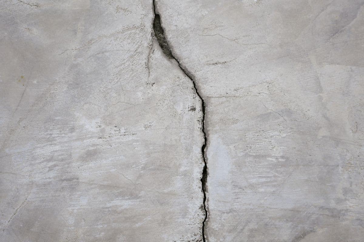Quality Foundation Repair Austin inspecting a severe vertical crack in a concrete foundation wall.