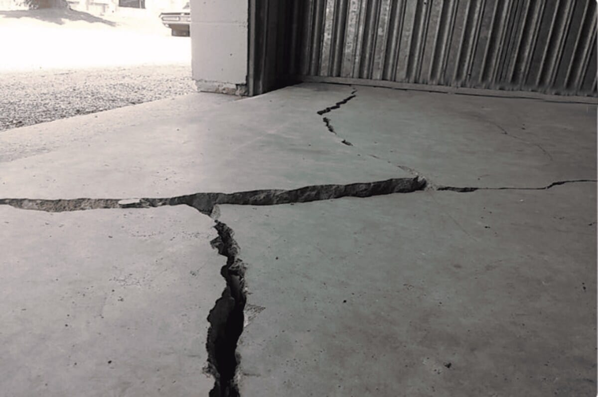 Quality Foundation Repair Austin inspecting severe cracks and unevenness in a concrete garage floor.