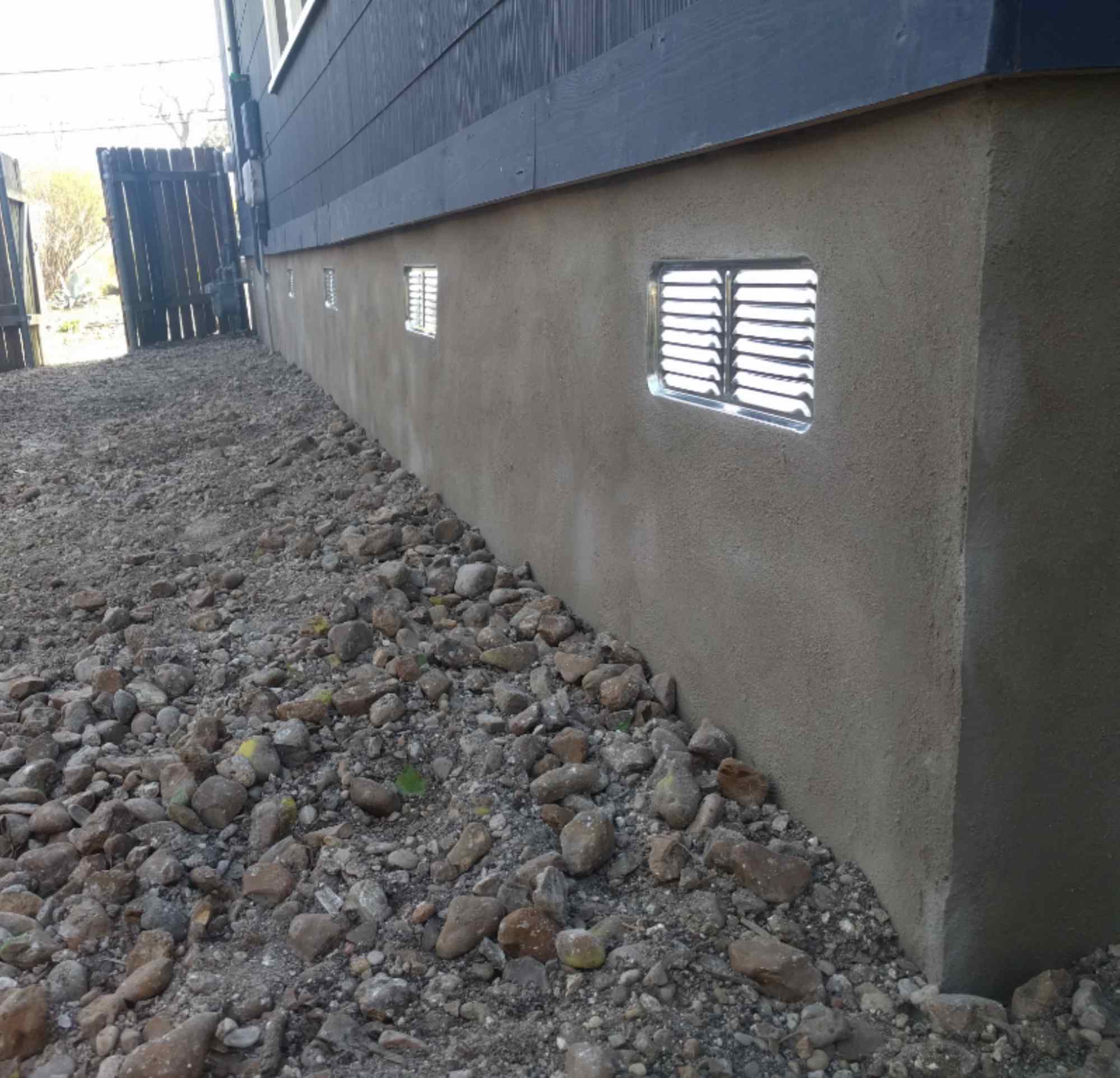 Quality Foundation Repair Austin installing crawl space vent covers on an exterior foundation wall.