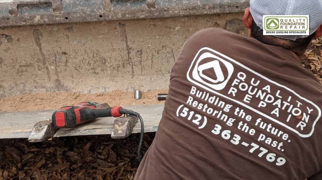 Quality Foundation Repair Austin team member performing house leveling services with a power tool.