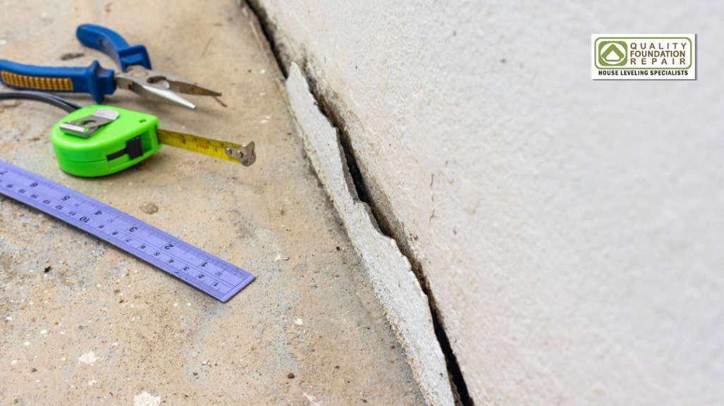 Quality Foundation Repair Austin inspecting a deep crack in a concrete foundation wall with measuring tape and tools.