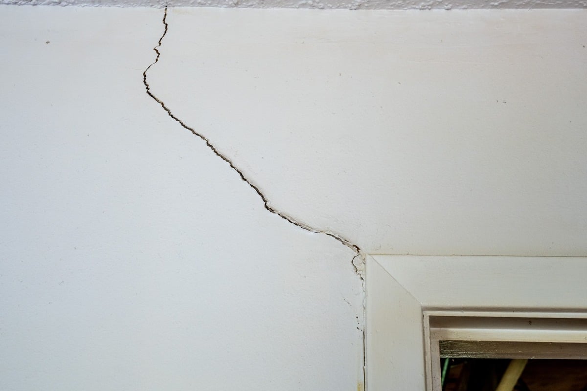Quality Foundation Repair Austin inspecting a crack running from a door opening across the ceiling.