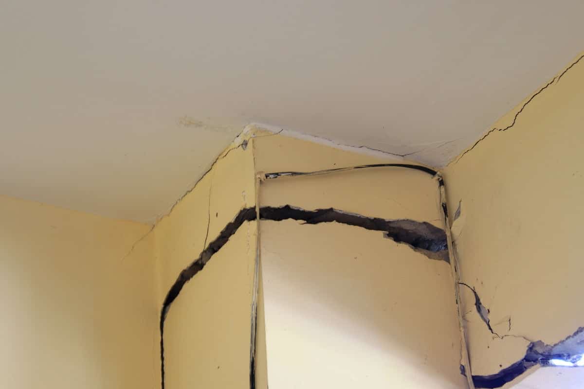 Quality Foundation Repair Austin inspecting wide cracks opening at an interior wall and ceiling corner.