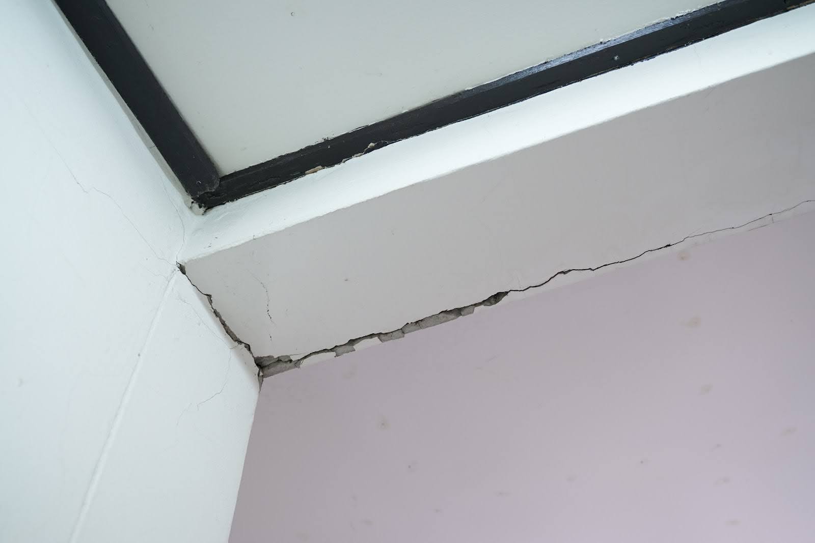 Quality Foundation Repair Austin inspecting a significant crack where an interior wall meets the ceiling.