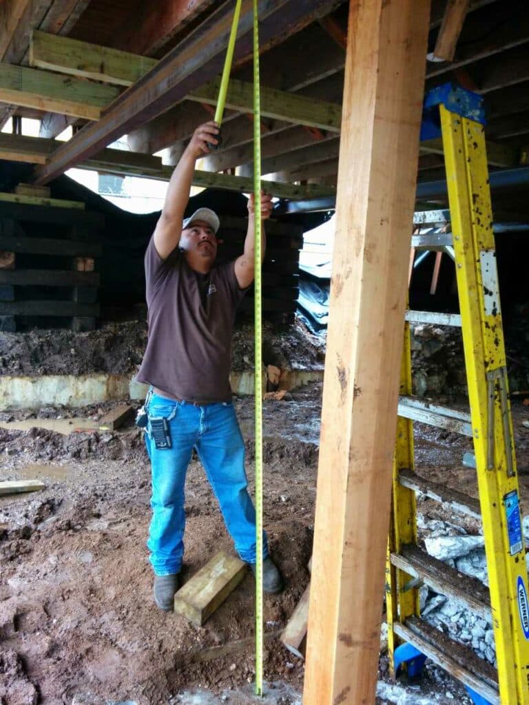 Quality Foundation Repair Austin technician measuring for crawl space structural repair and beam support.