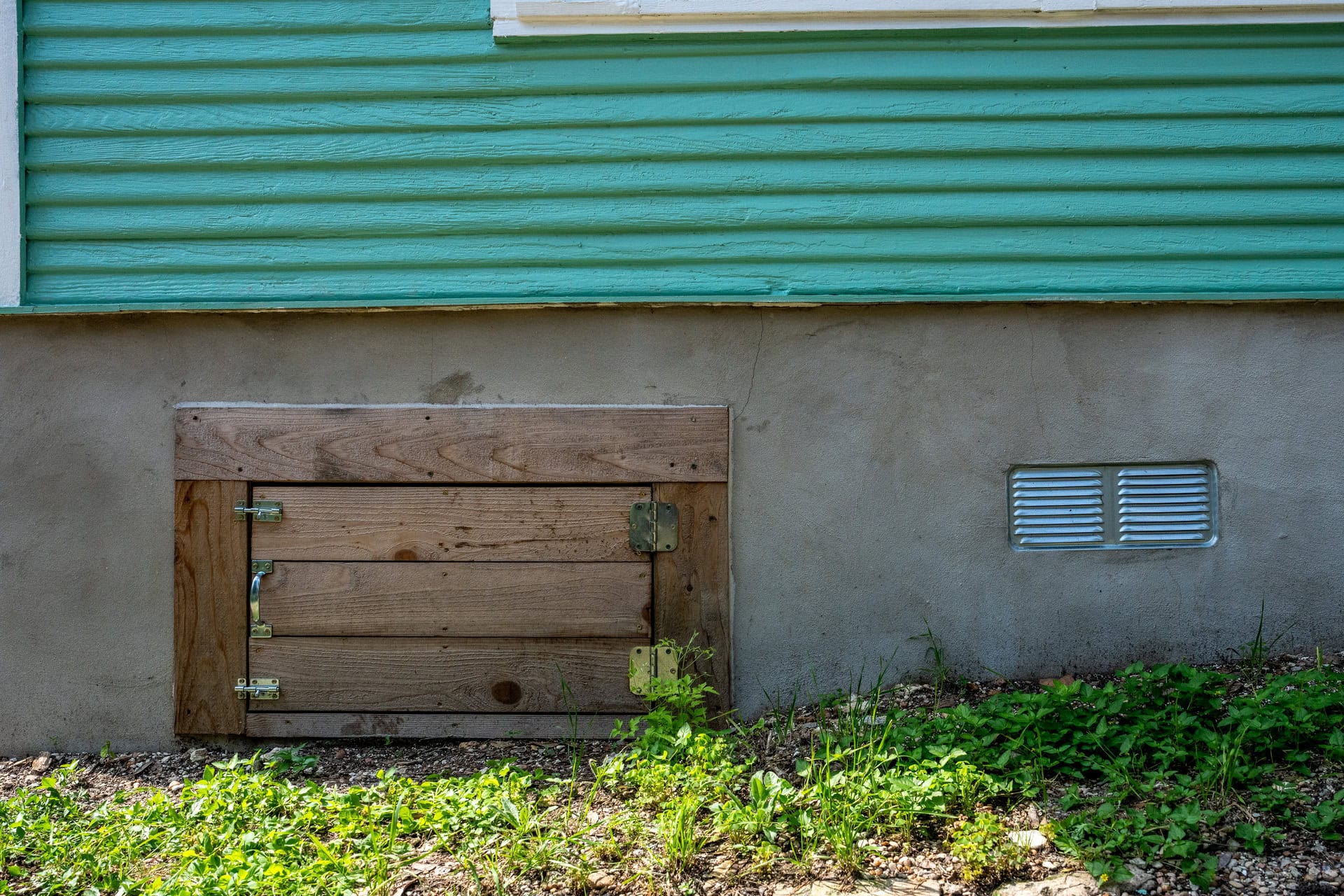 Quality Foundation Repair Austin crawl space access door and vent set into an exterior foundation wall.