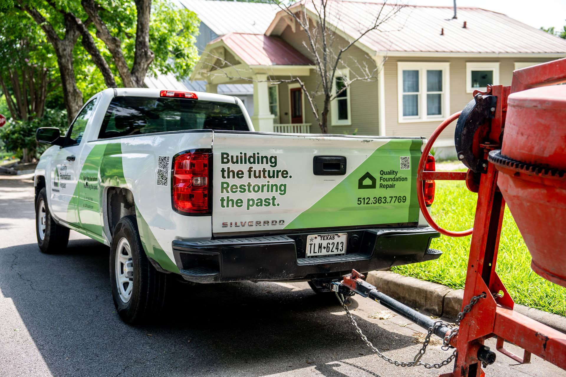 Quality Foundation Repair Austin branded truck towing a mixer to a residential job.