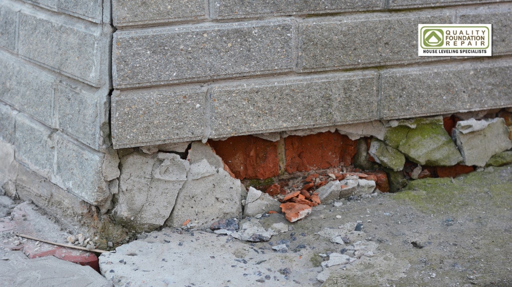 Quality Foundation Repair Austin inspecting a failing concrete block foundation with displaced brick.