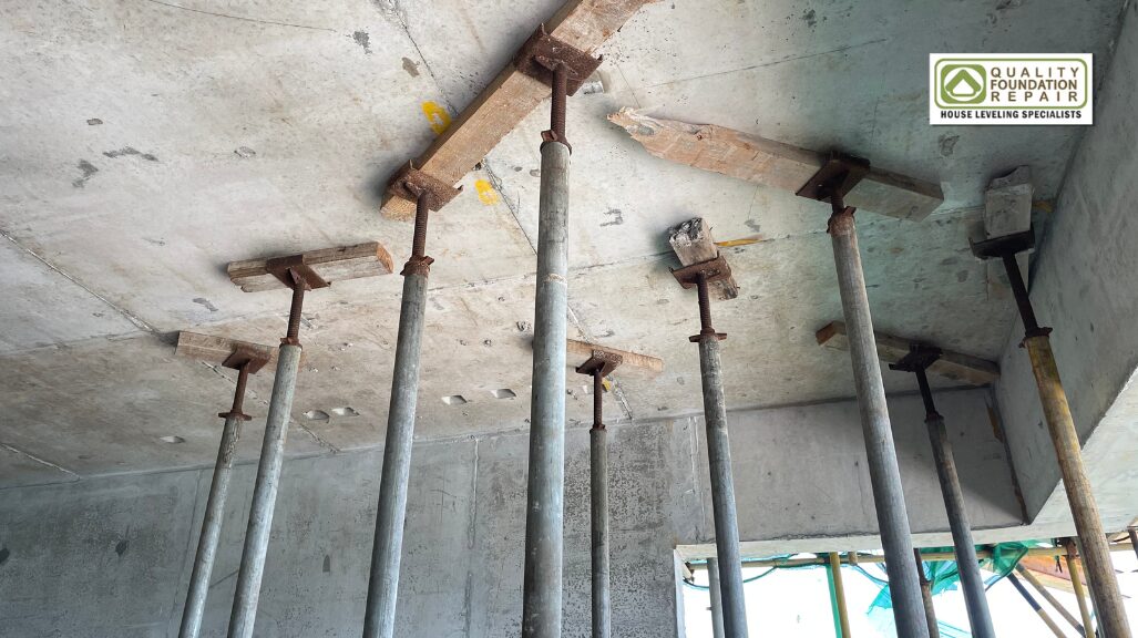 Quality Foundation Repair Austin steel shoring posts carrying a concrete slab on a larger job.