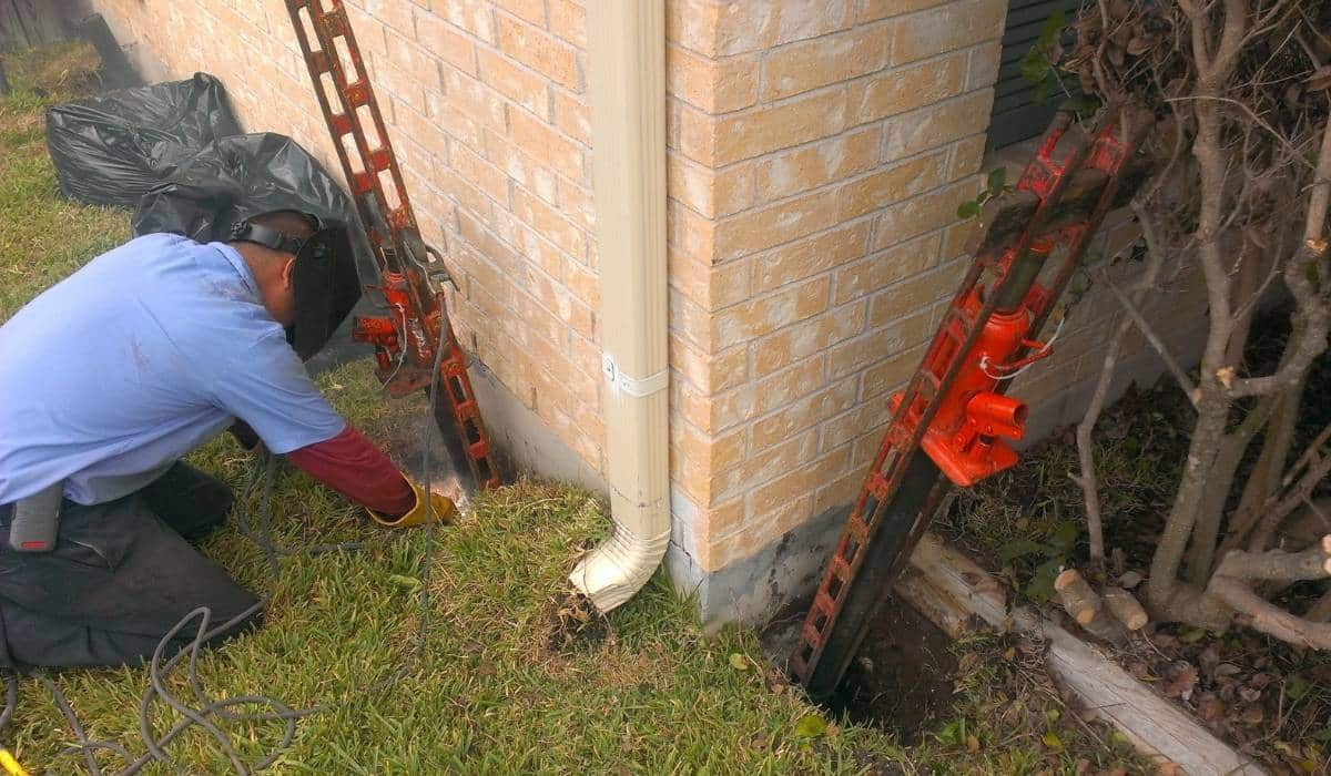 Quality Foundation Repair Austin technician installing an Adjust-A-Pier at a home's exterior foundation.