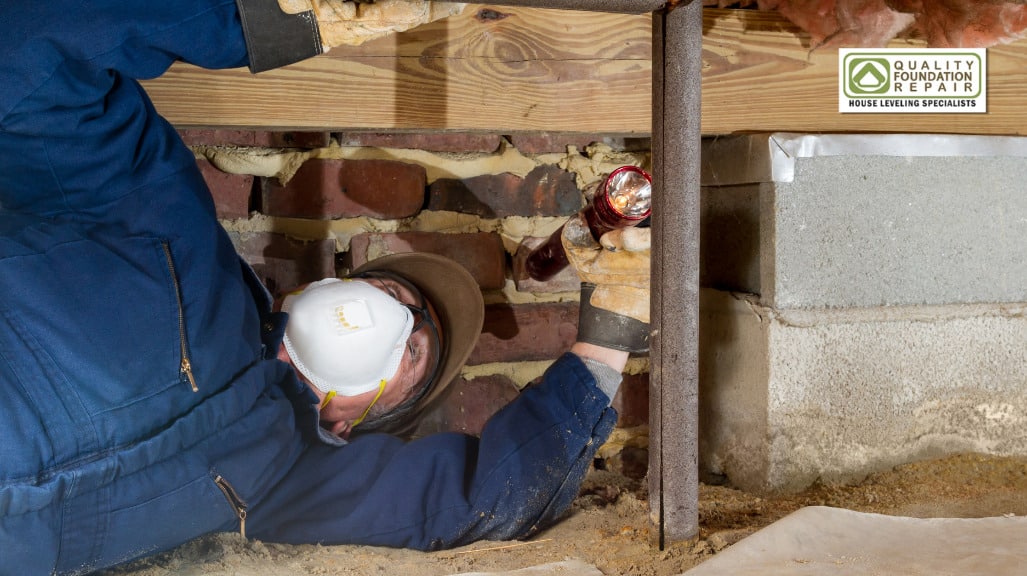 Quality Foundation Repair Austin technician inspecting brick foundation in a crawl space with a flashlight.