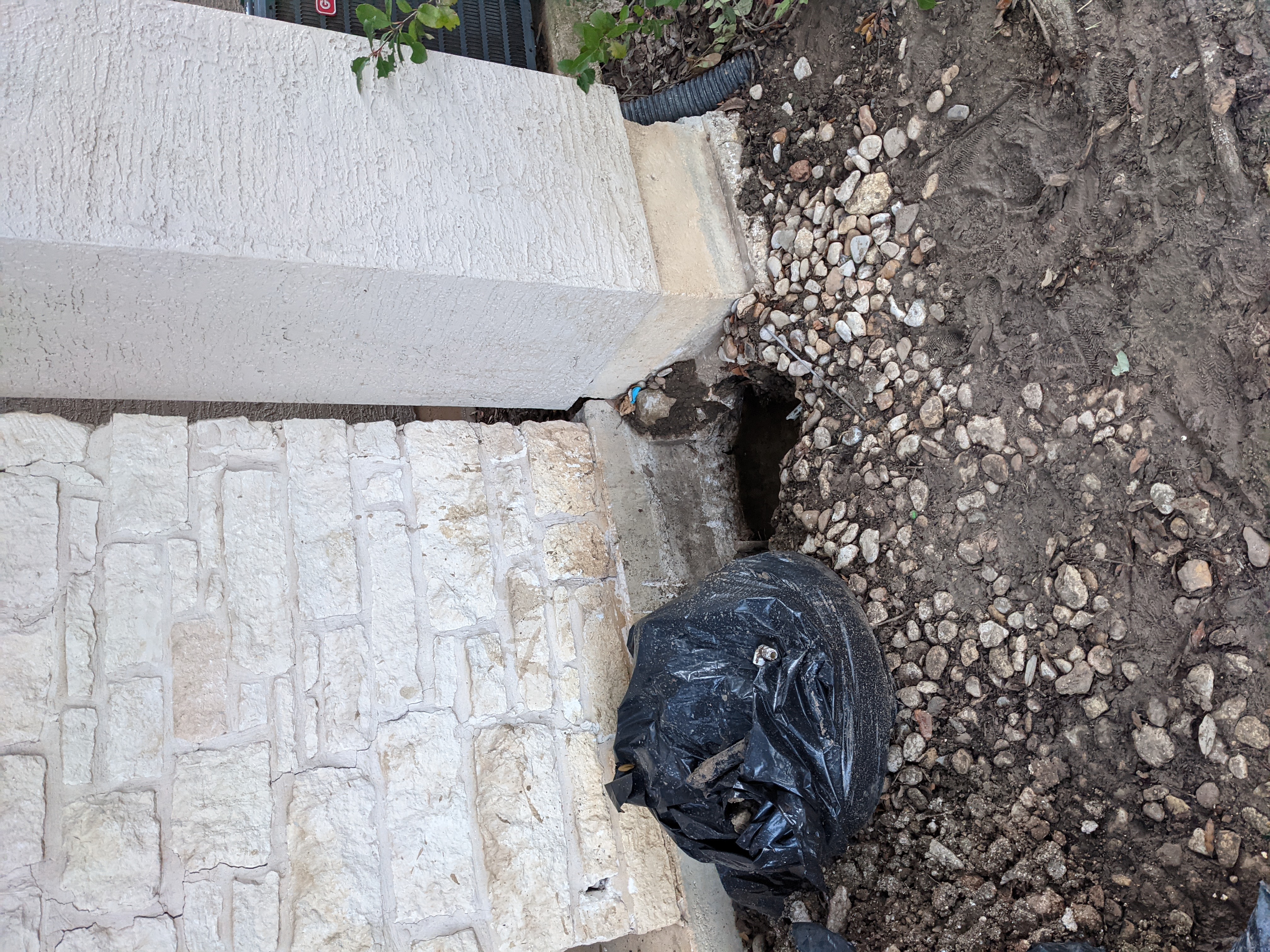 Quality Foundation Repair Austin inspecting exterior foundation with improper drainage causing muddy conditions.
