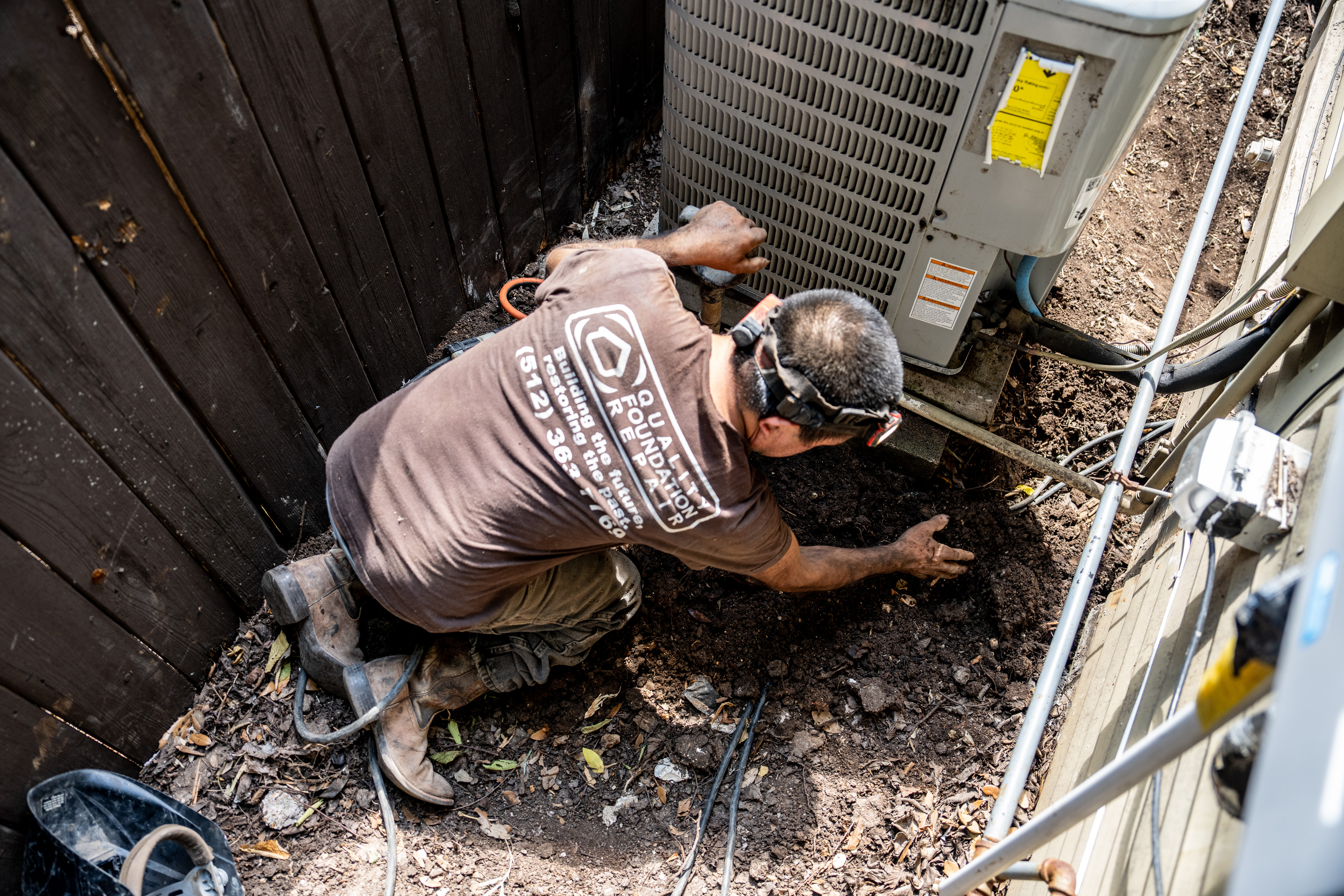 Quality Foundation Repair Austin technician inspecting soil around a residential foundation