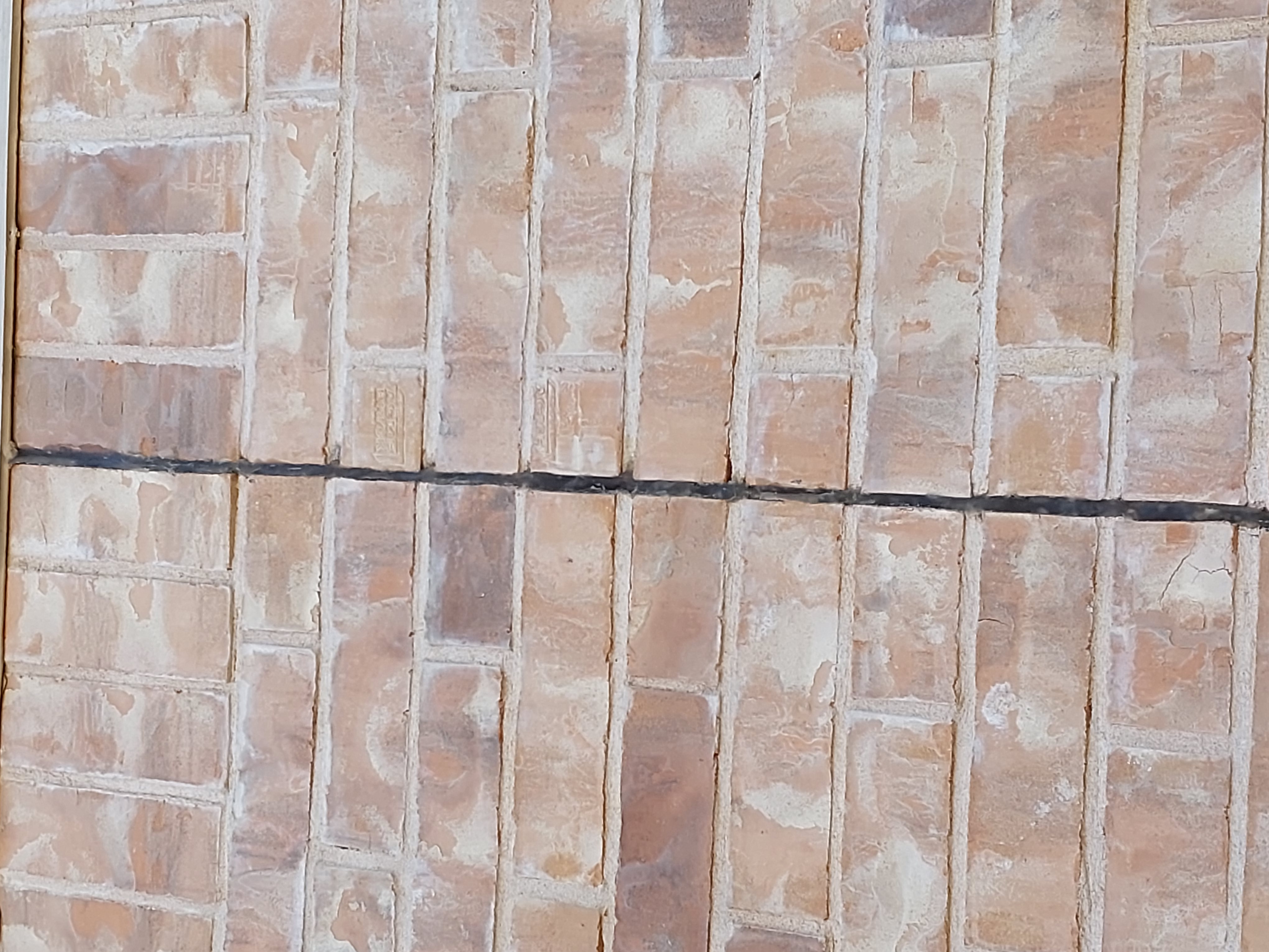 Quality Foundation Repair Austin inspecting an expansion joint in a brick foundation wall.