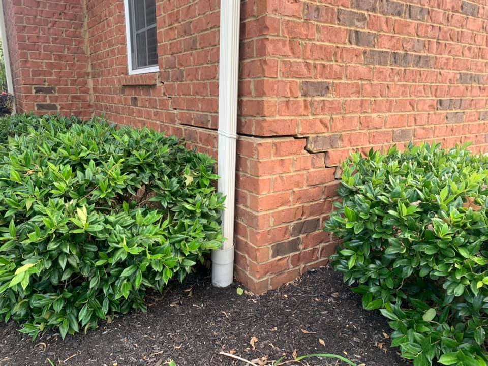 Stair step cracks in a brick exterior wall indicating a sinking foundation.