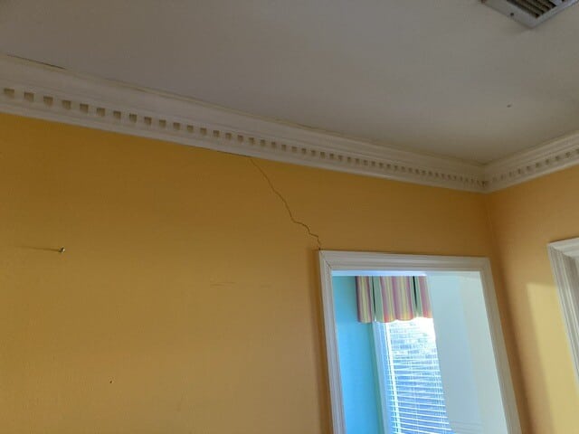 Ground Up Foundation Repair, Waterproofing and Concrete Leveling inspecting a diagonal crack in an interior wall near the cei