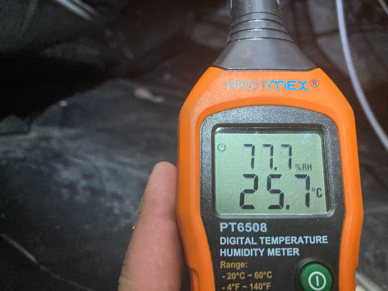 Checking high humidity in a crawl space with a digital humidity meter.