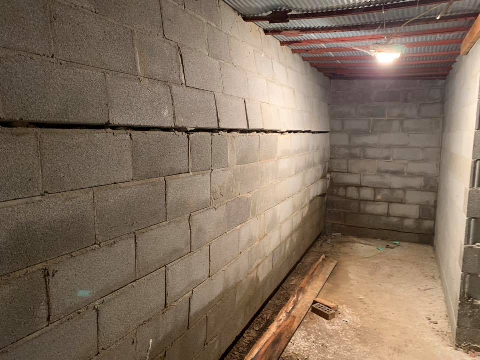 Ground Up Foundation Repair, Waterproofing and Concrete Leveling inspecting a significant horizontal crack in a basement cind