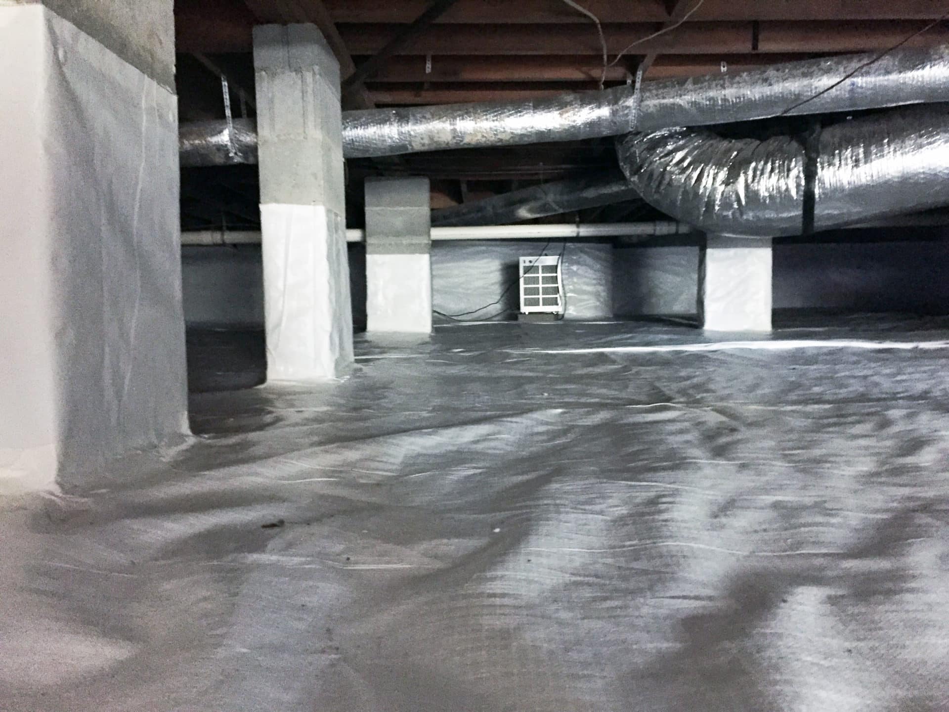 Installing a CleanSpace vapor barrier and dehumidifier in a crawl space.