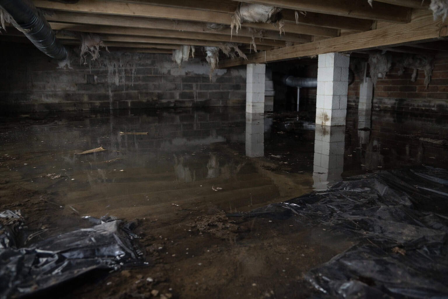 Ground Up Foundation Repair, Waterproofing and Concrete Leveling inspecting a severely flooded crawl space with standing wate