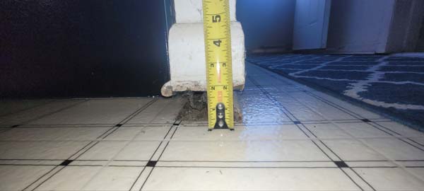 Ground Up Foundation Repair, Waterproofing and Concrete Leveling using a measuring tape to inspect floor settlement and saggi