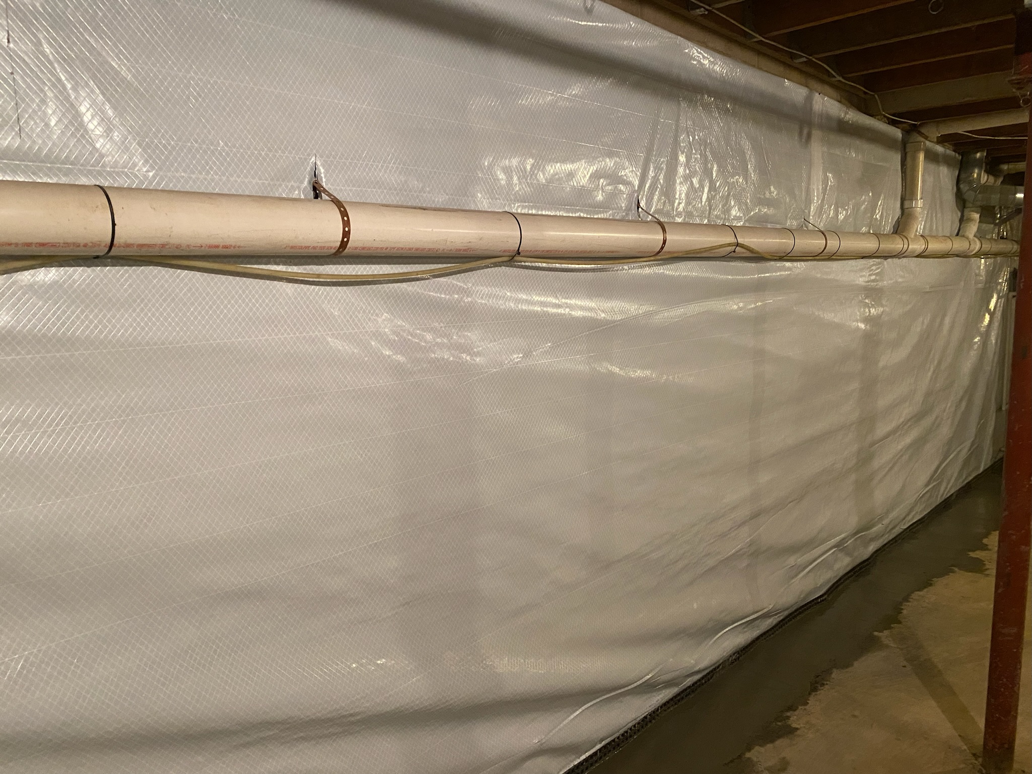 Full length basement wall covered by a completed vapor barrier