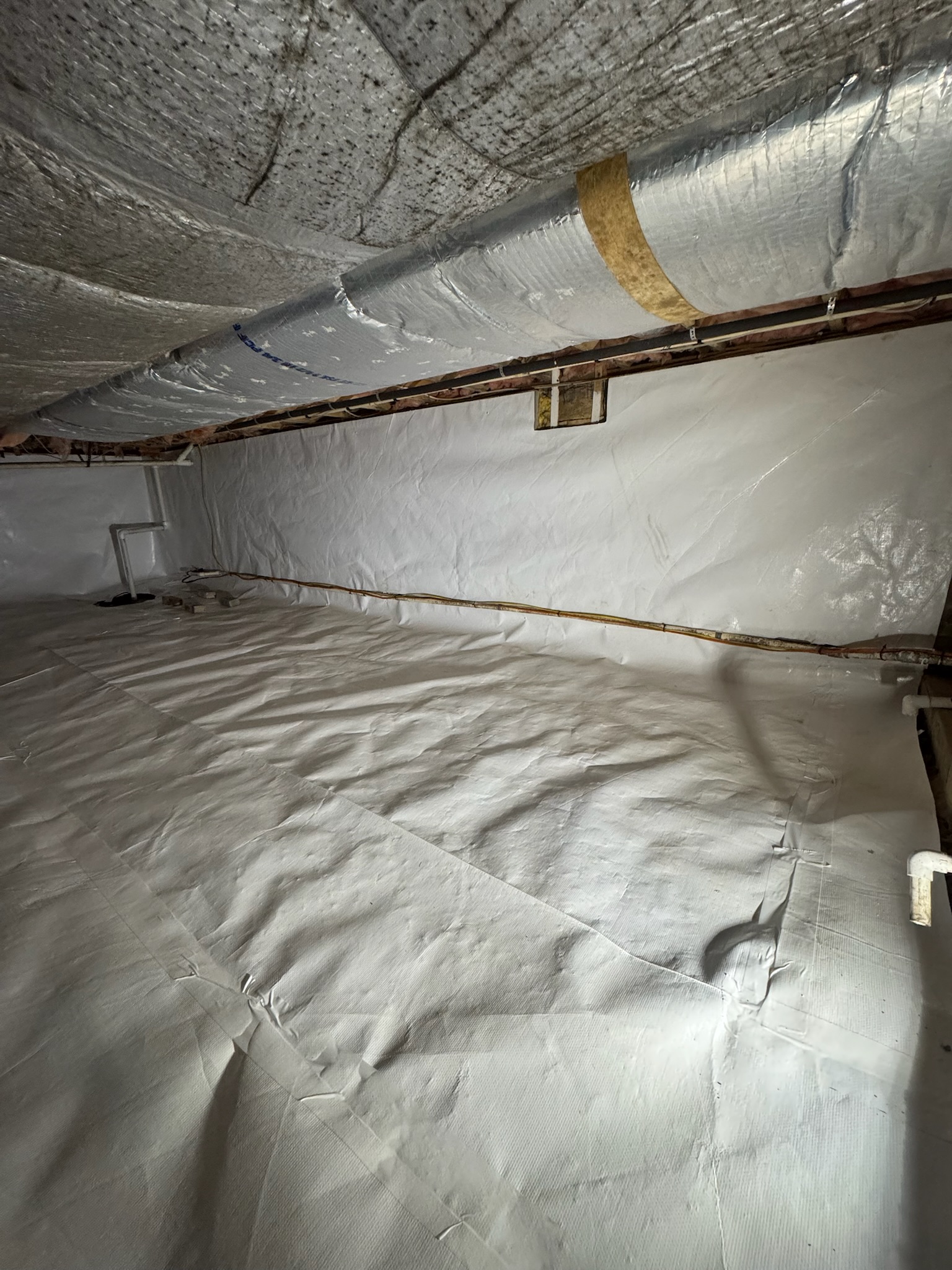 Moldy insulation being removed alongside a newly installed vapor barrier in a Maryland crawl space