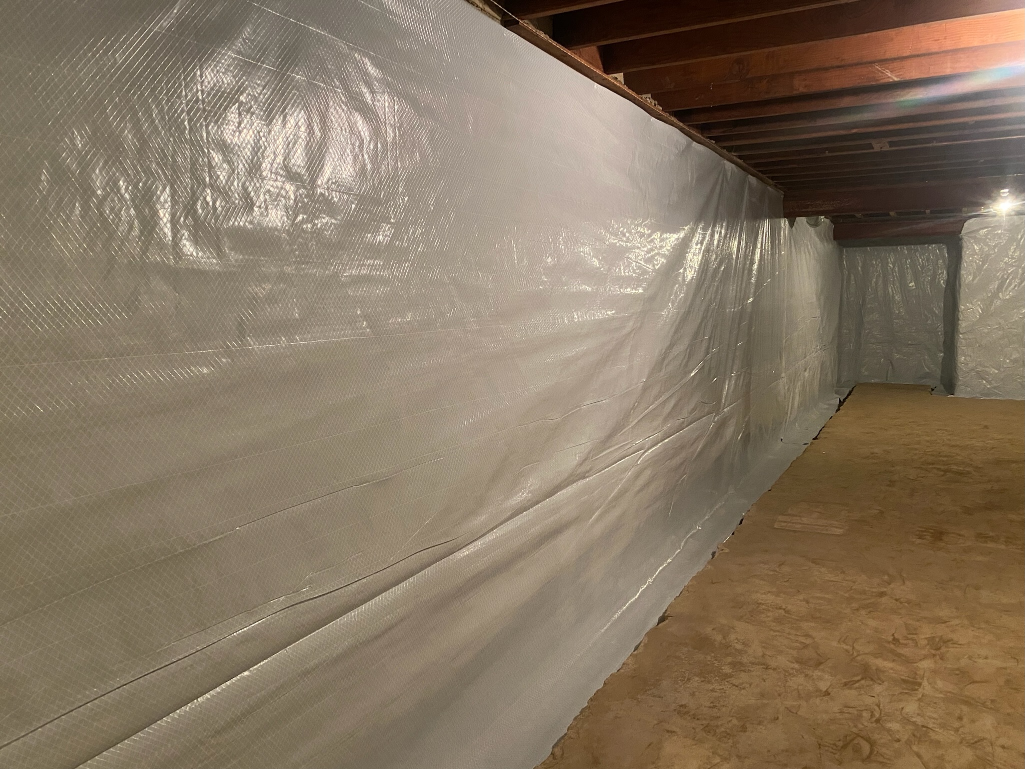 Completed vapor barrier running the full height of a Maryland basement wall