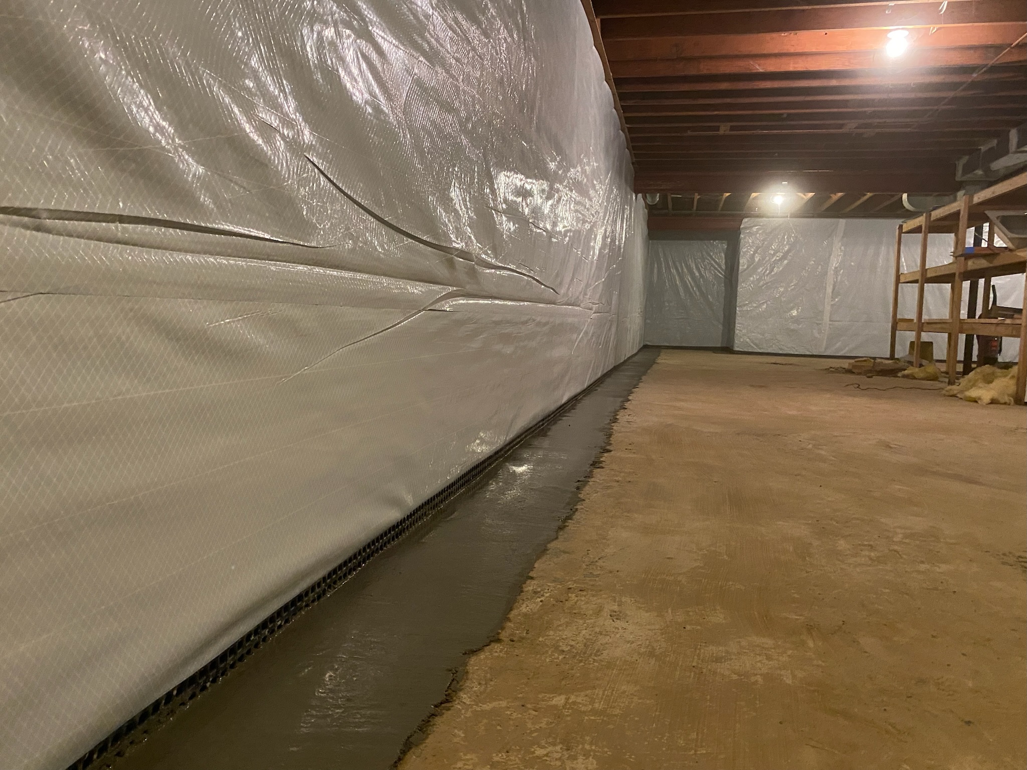 Barrier tucked into the drainage channel at the base of a basement wall