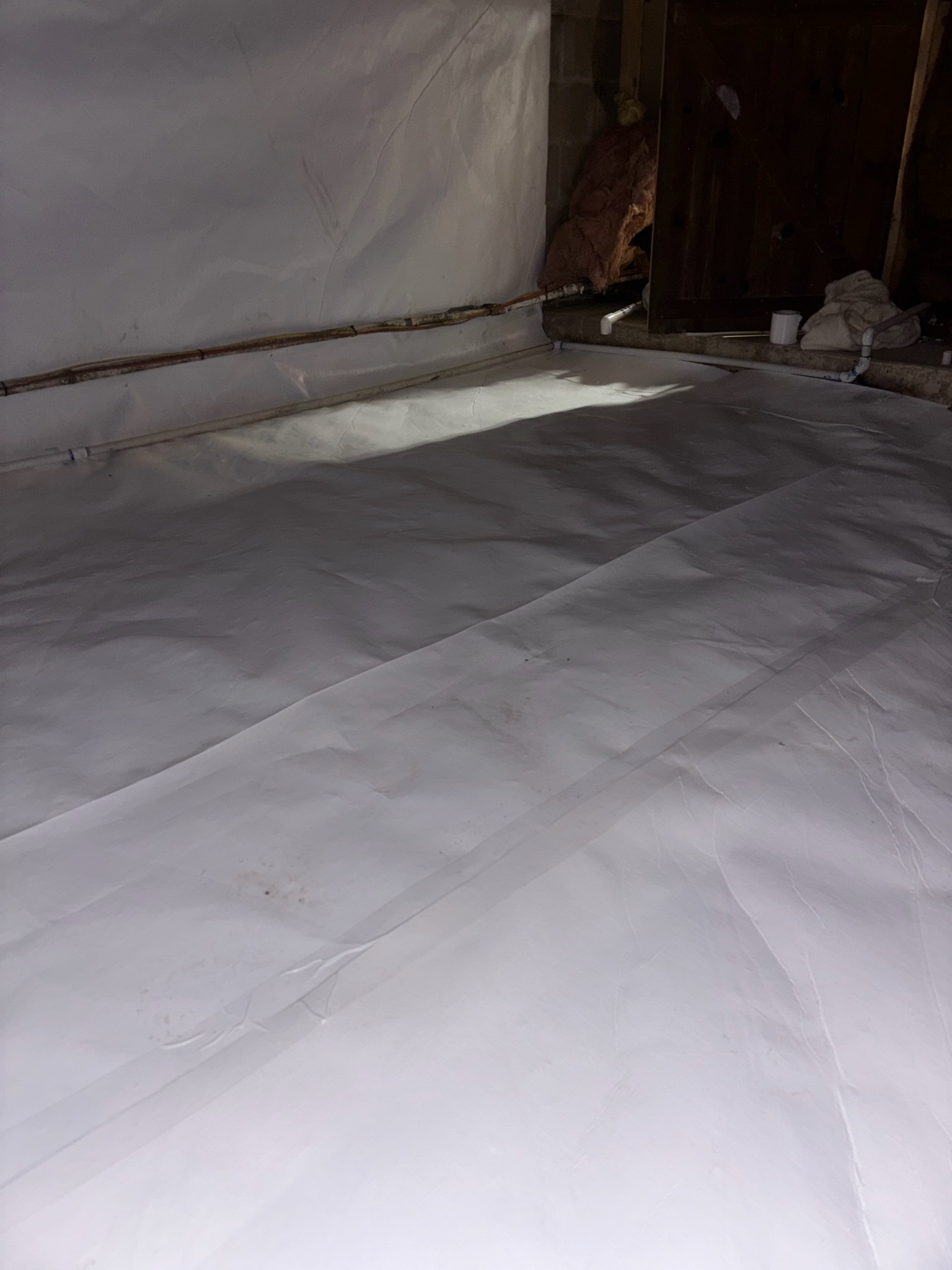 White floor liner laid across a crawl space floor