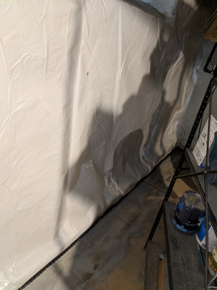 Oriole Basement Waterproofing installing a white crawl space vapor barrier for moisture control.