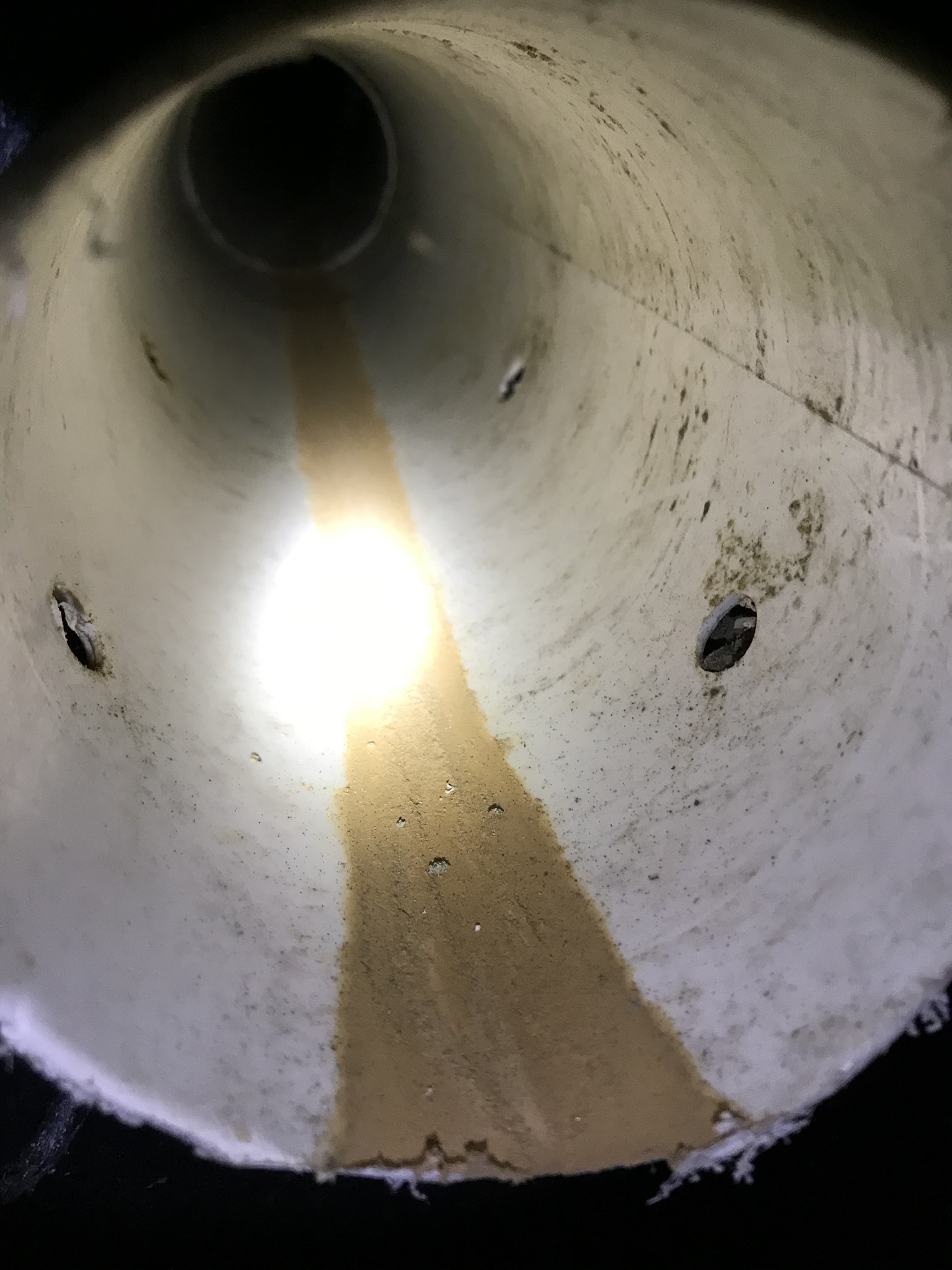 Sediment buildup in a Maryland basement drainage pipe, an early sign of sump pump strain