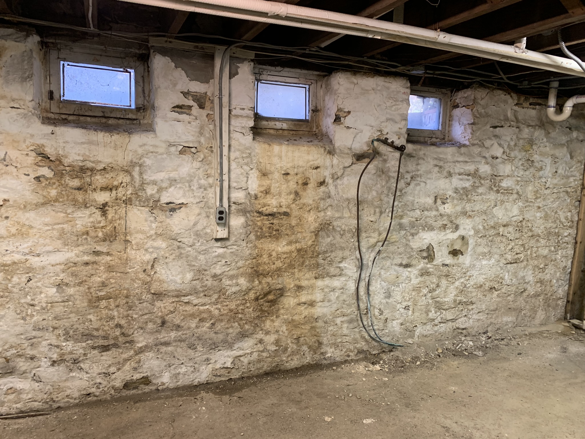 Peeling paint and moisture stains on a Maryland basement wall from water damage
