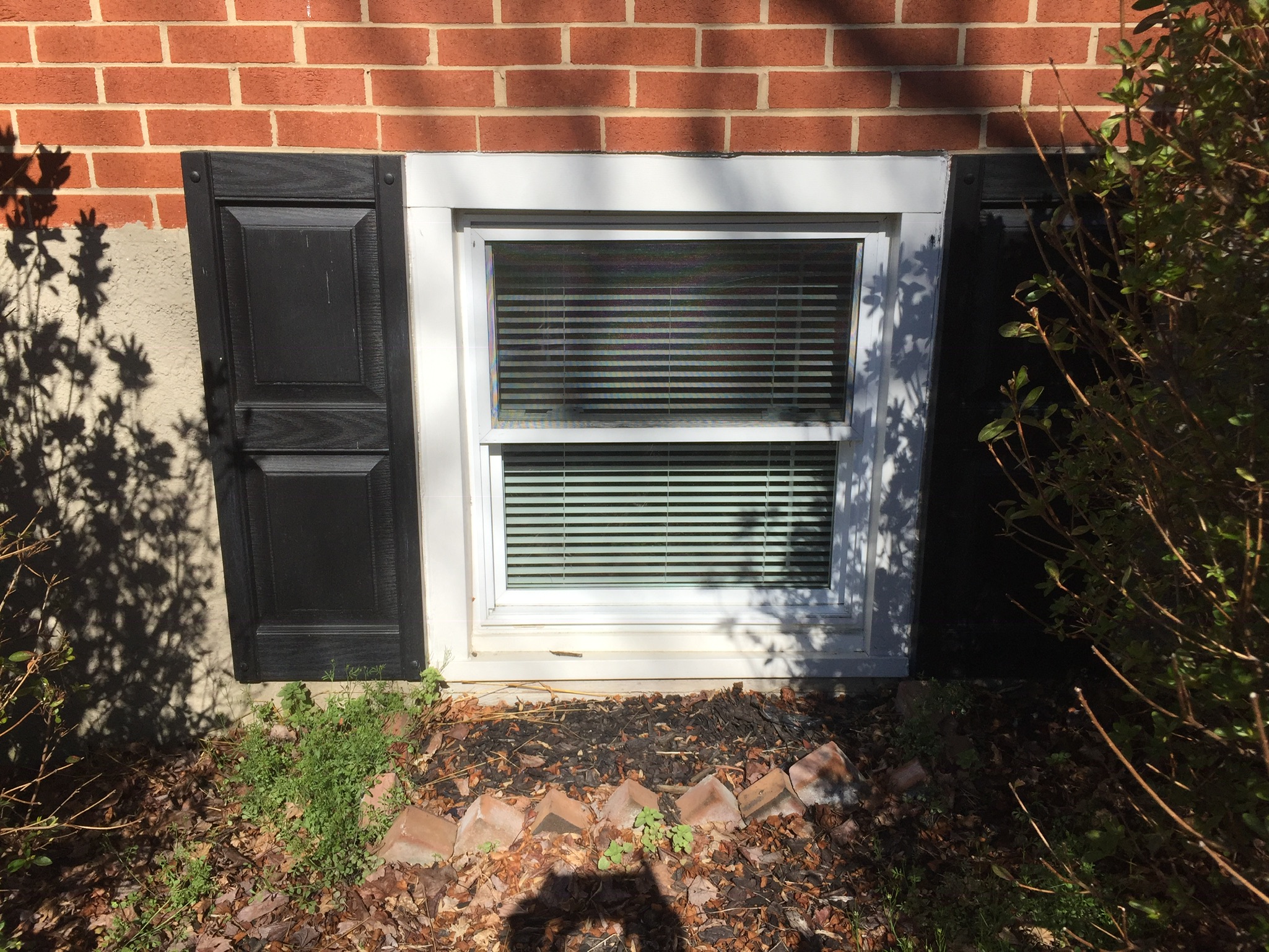 Older basement window with brick siding showing signs of egress frame failure in Maryland