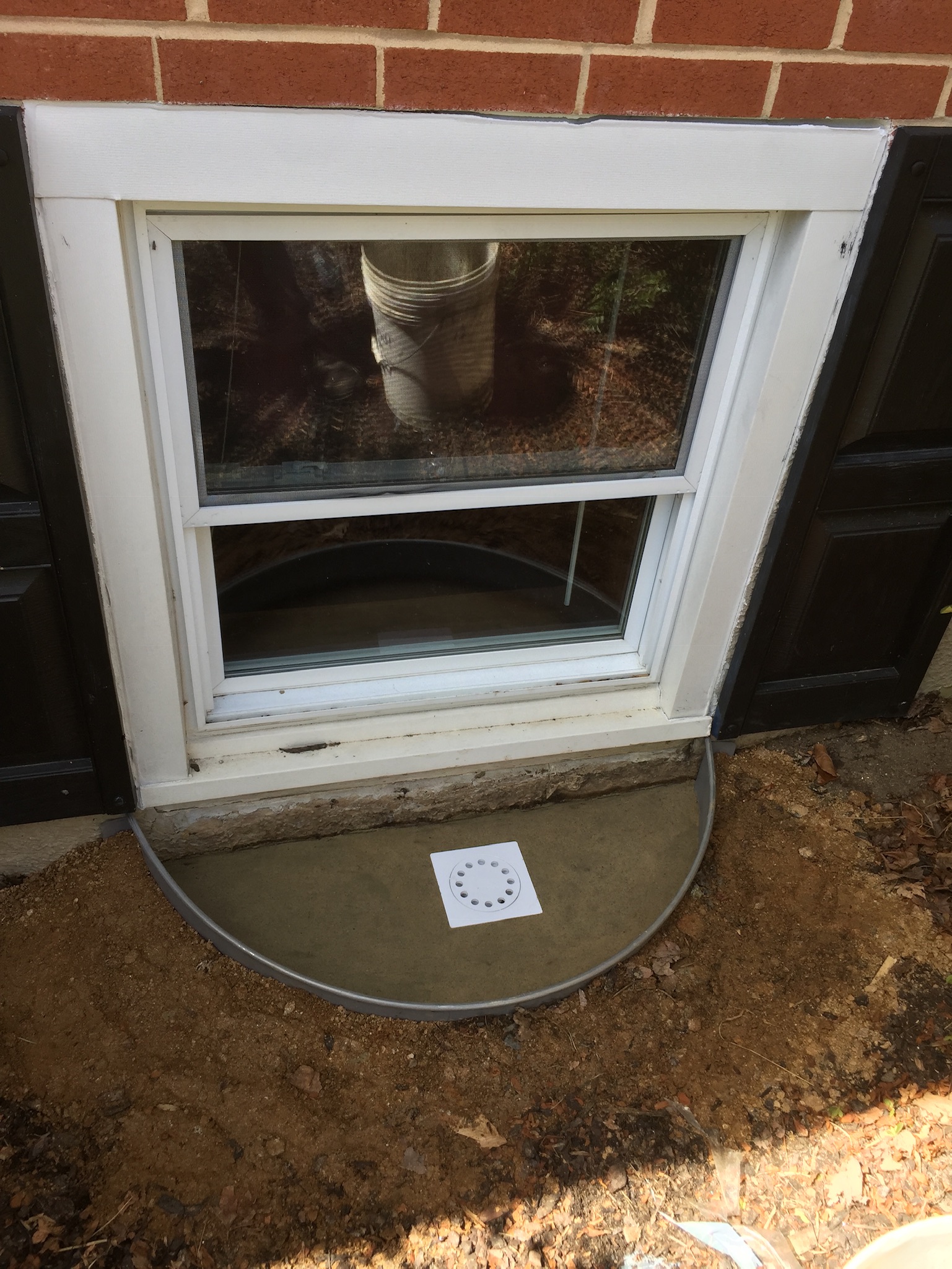 Egress window with drainage system inspected before replacement in a Maryland basement