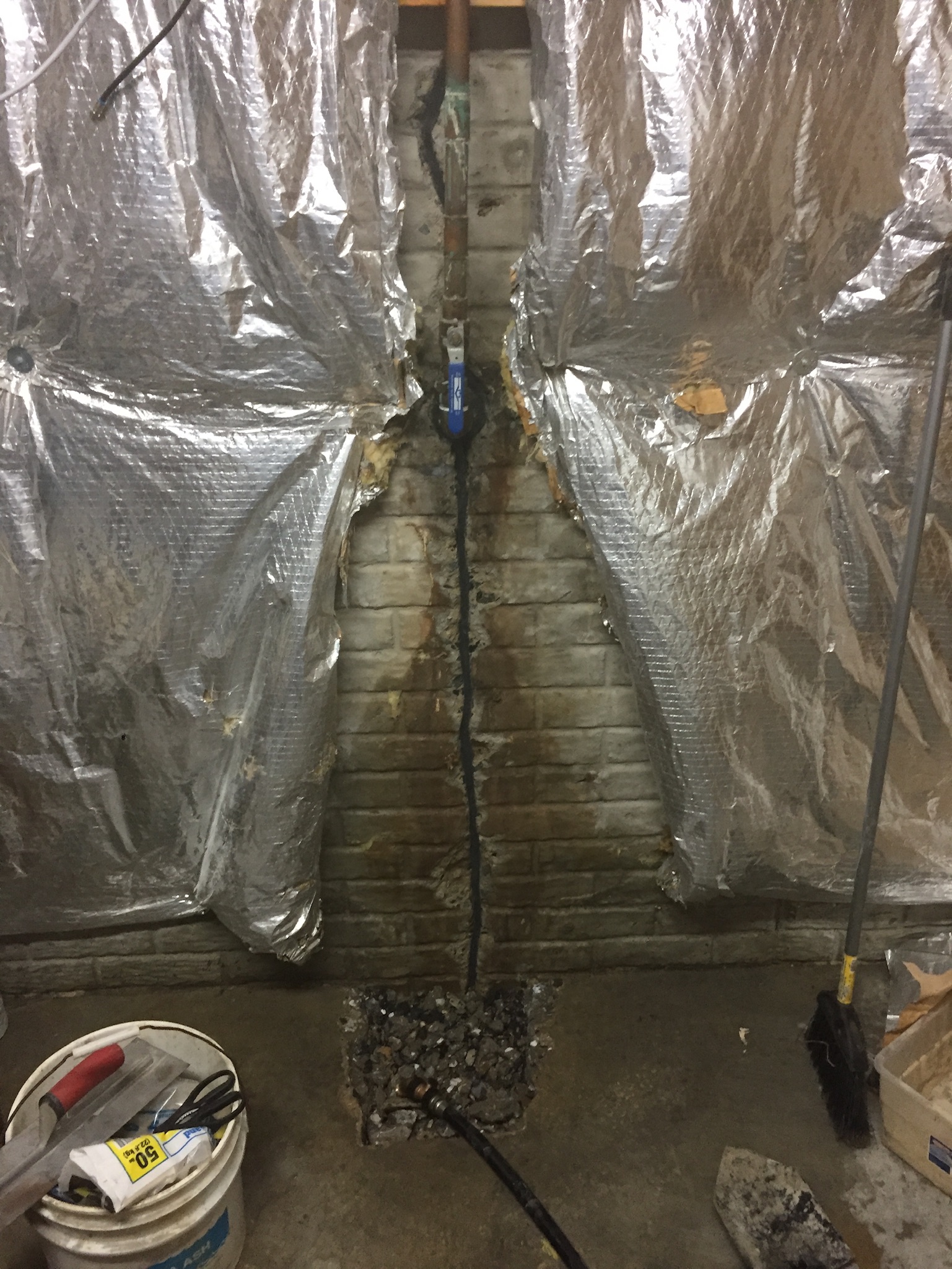 Vertical crack in a brick basement foundation wall with water staining