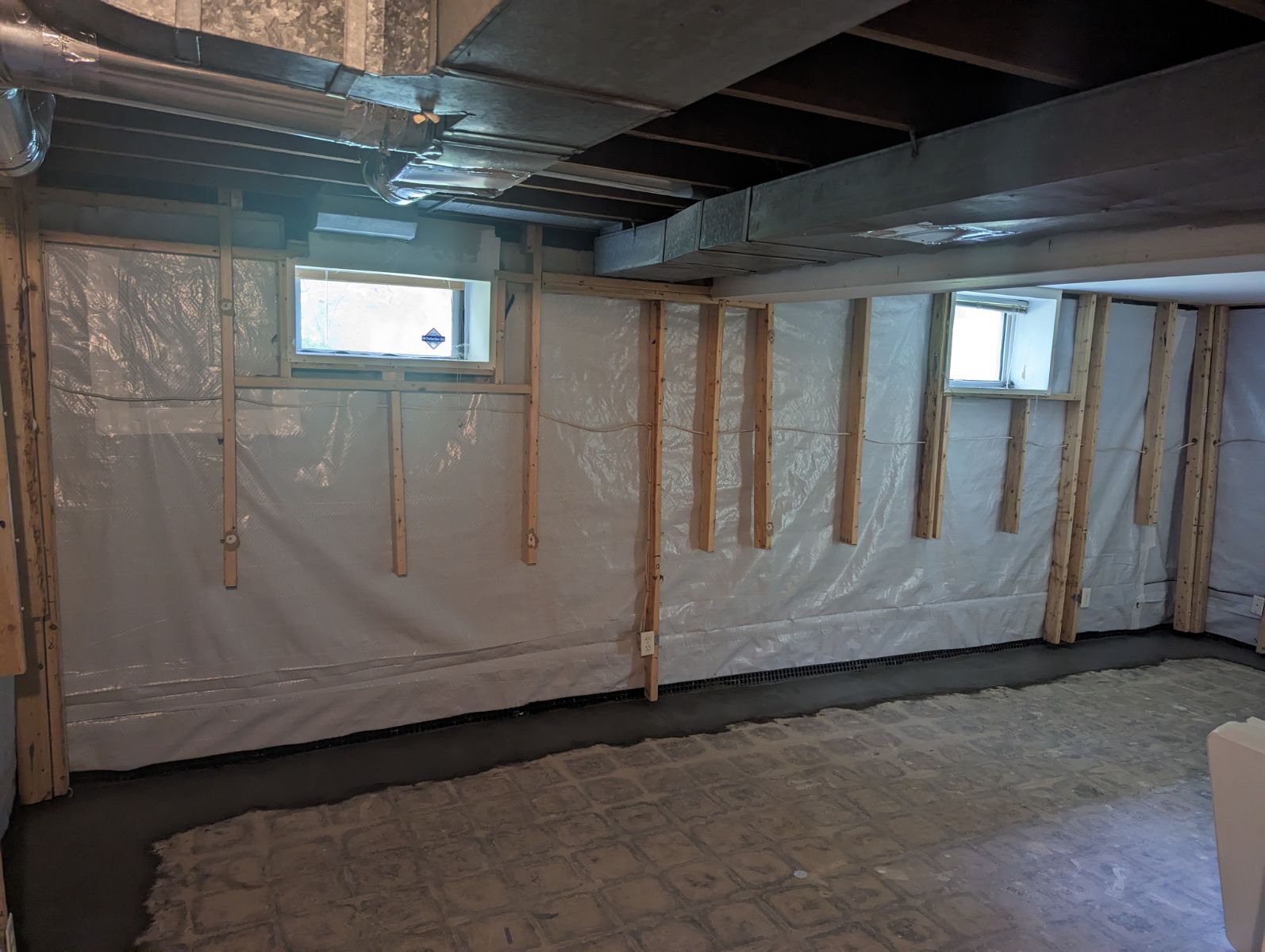 Barrier installed behind wall framing across a full basement room