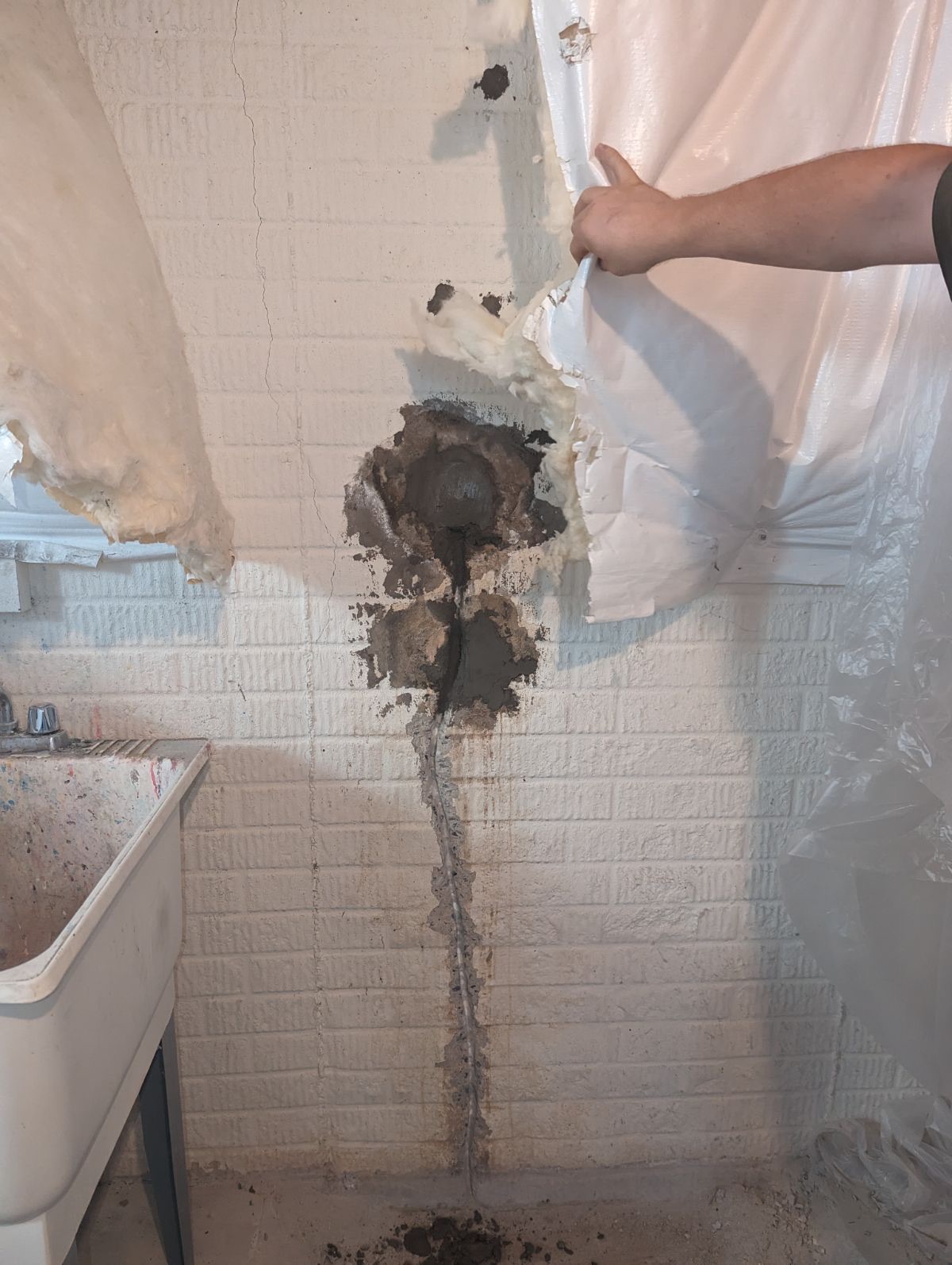 Vertical crack in a basement wall behind a vapor barrier, the kind of foundation movement that can produce interior drywall cracks in a Maryland home