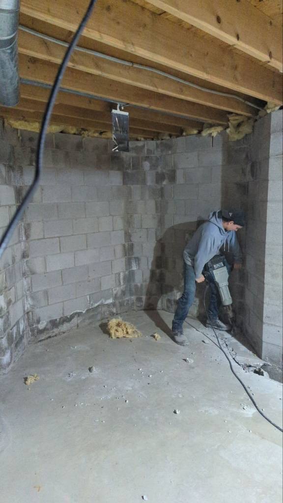 OBW technician using jackhammer and saw to cut basement perimeter concrete