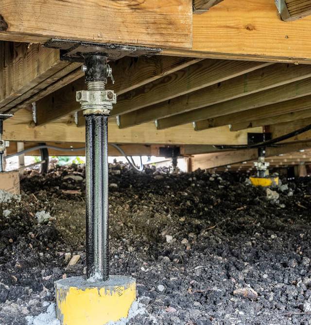 Quality Foundation Repair Austin installing adjustable steel jacks to stabilize a crawl space foundation and wooden joists.