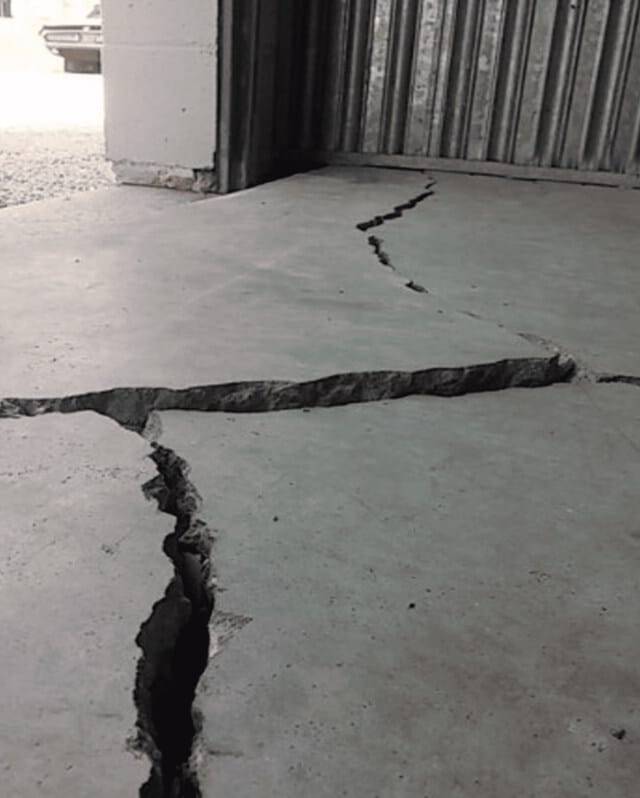 Quality Foundation Repair Austin inspecting severe cracks and unevenness in a concrete garage floor, typical signs of foundat