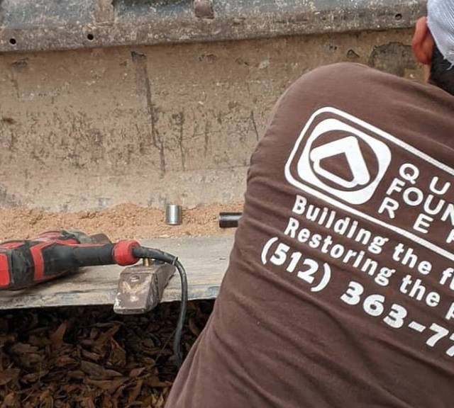Quality Foundation Repair Austin team member performing house leveling services with a power tool.