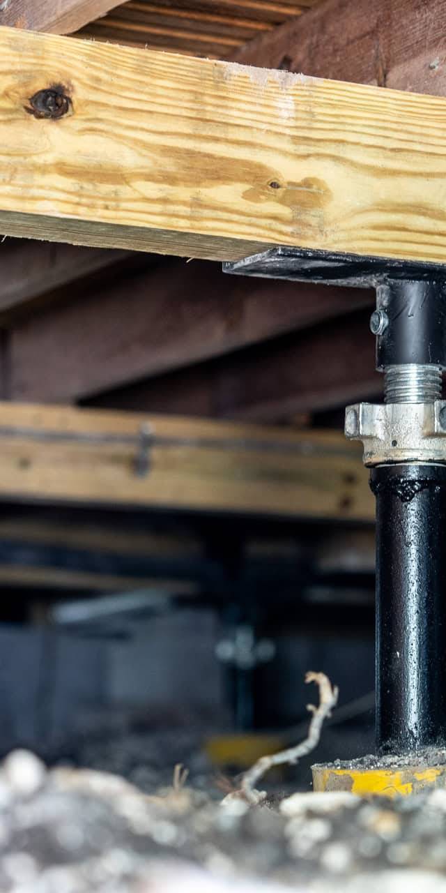 Quality Foundation Repair Austin stabilizing a crawl space with adjustable steel jacks supporting wooden floor joists.