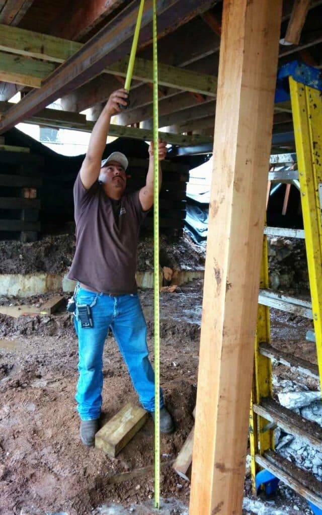 Quality Foundation Repair Austin technician measuring for crawl space structural repair and beam support.