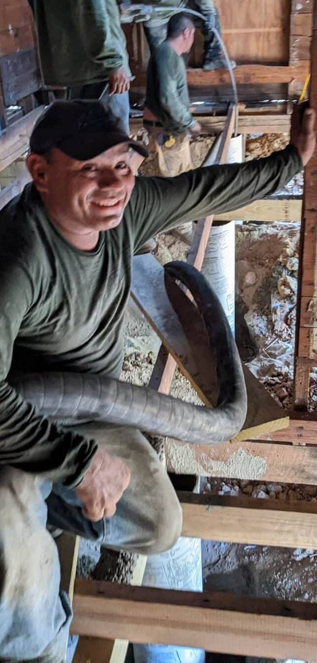 Quality Foundation Repair Austin team member smiling during structural crawl space repair work, reinforcing floor joists.