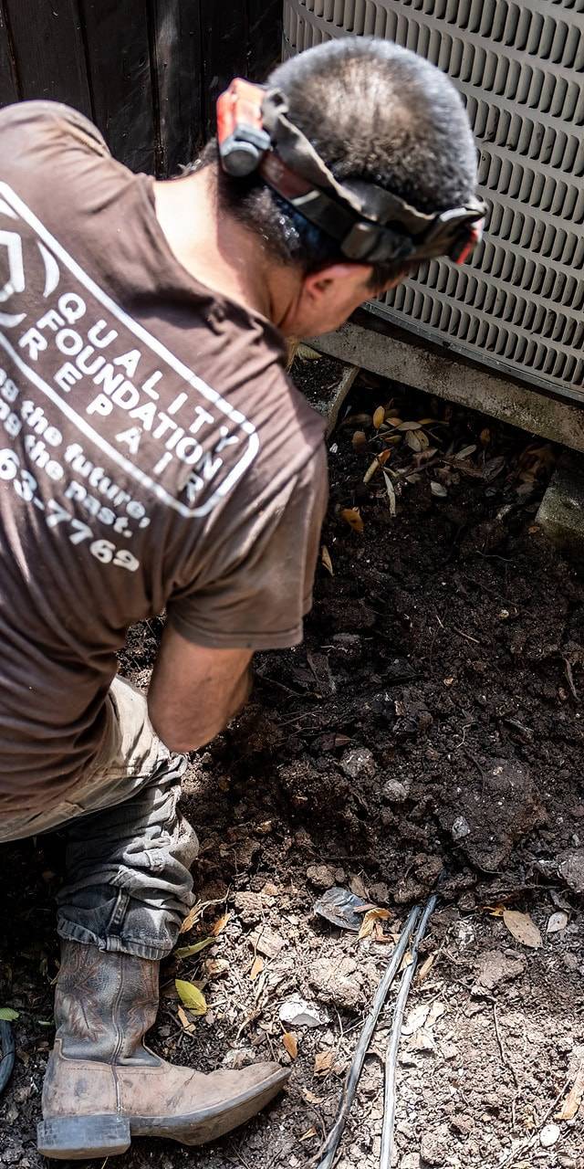 Quality Foundation Repair Austin technician performing foundation inspection in exterior residential area.