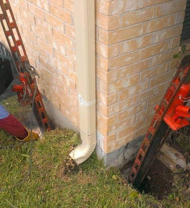 Quality Foundation Repair Austin technician installing an Adjust-A-Pier at a home's exterior foundation.